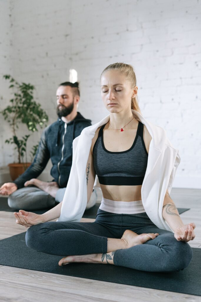 Woman and man in meditation stance sitting on yoga mats