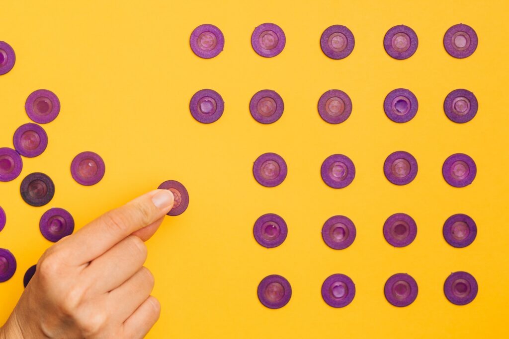 Hand organizing purple tokens on a yellow background