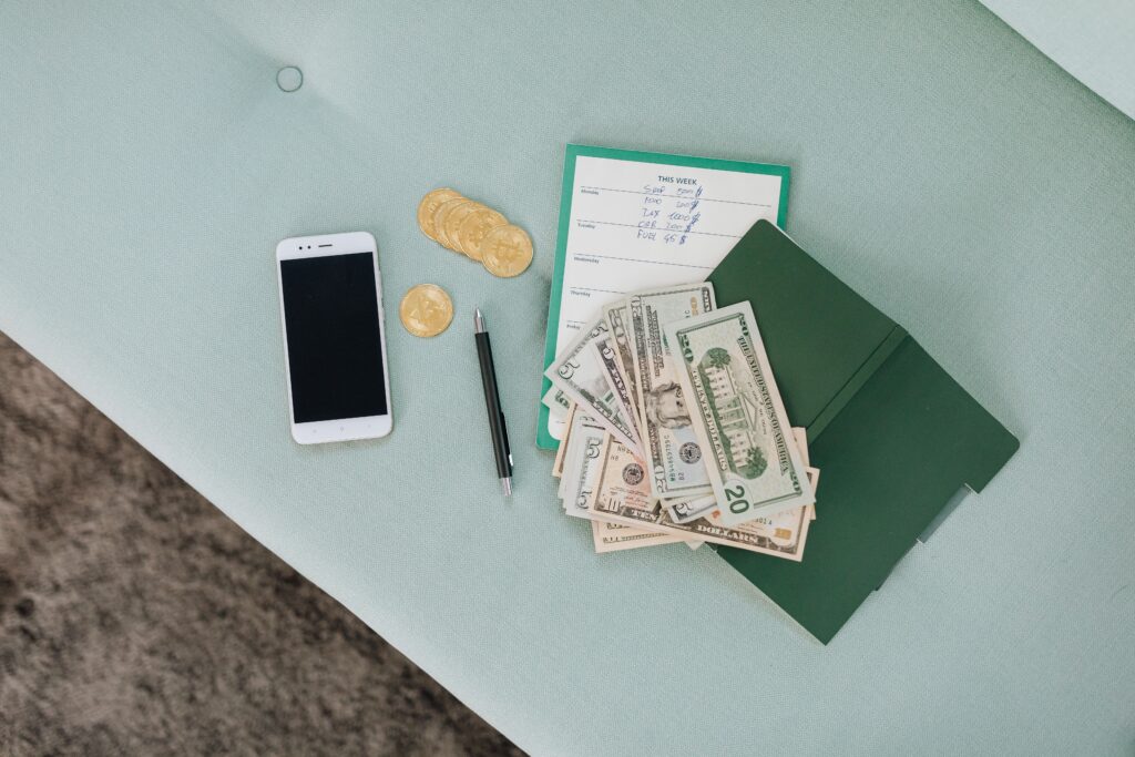 Money next to a weekly planner, folder, and phone