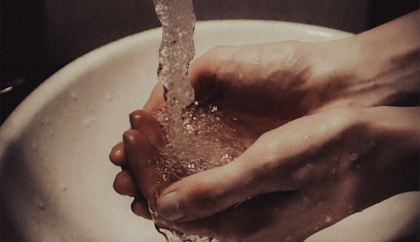hands under running water in a sink