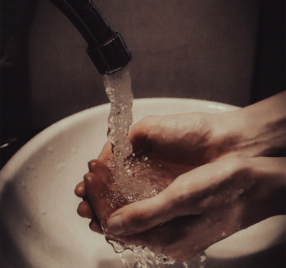 hands under running water in a sink
